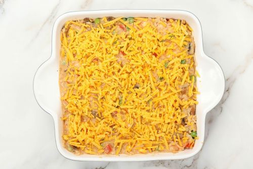 Step 8: Pour the mixture of shrimp and rice into a baking dish. Spread out evenly. Sprinkle shredded cheddar cheese on top.